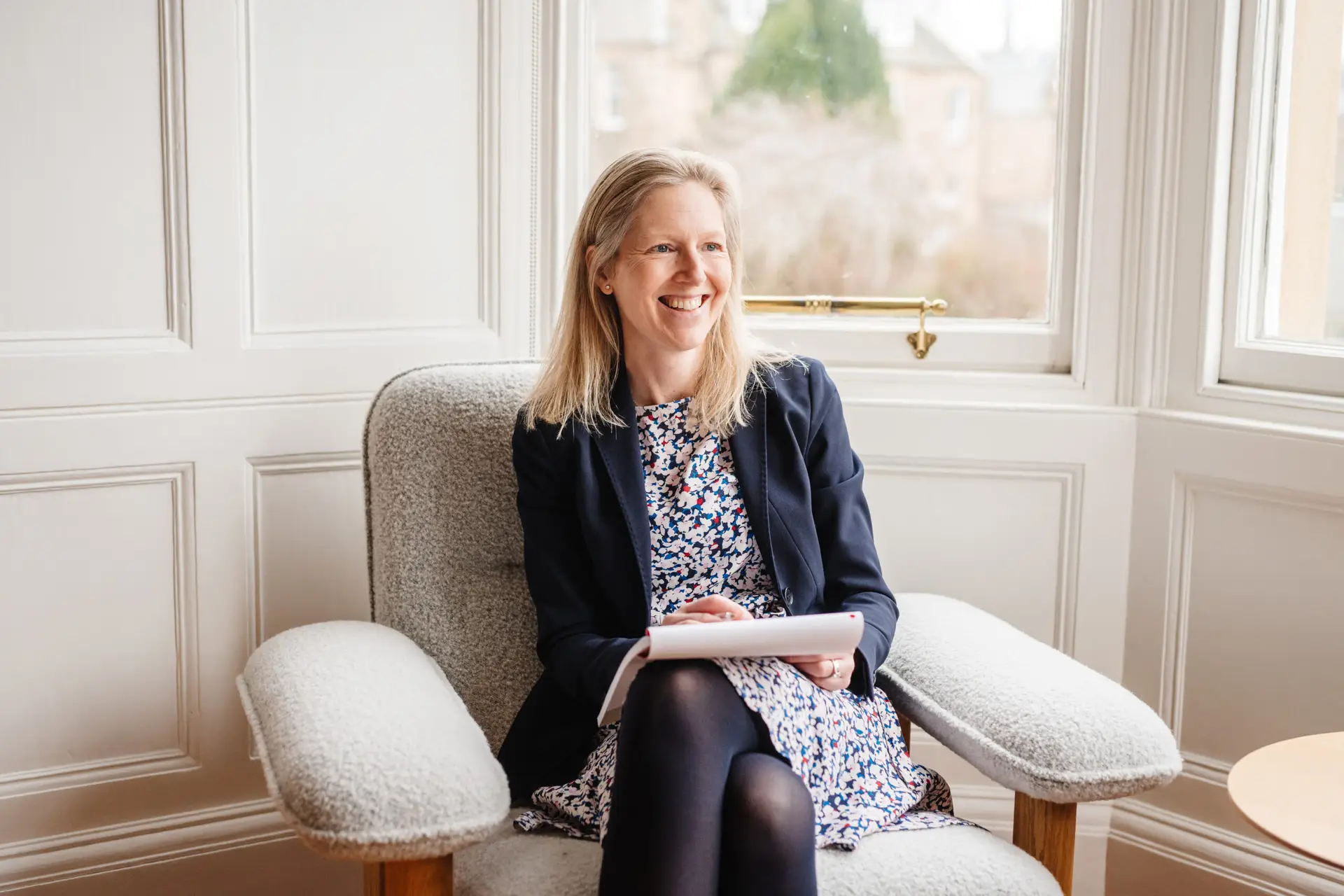 Charlotte Connolly seated in her coaching space, natural light from a large window